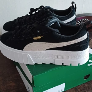 Puma Mayze Wn's sneakers svart/vit - Säljer ett par Puma Mayze Wn's sneakers i svart mocka med vit sula och vit Puma-logga på sidan. Skorna har en chunky plattformssula och klassisk snörning. Perfekta för dig som gillar streetstyle och vill ha lite extra höjd.