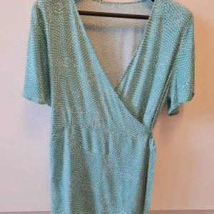 Omlottstopp från Zizzi strl 48 - Säljer en omlottstopp med kort ärm från Zizzi. Toppen har v-ringning och knytband i midjan. Storlek 48 (Zizzi M). 100% viskos. Etiket har klippts. Kan hämtas i Vallentuna.