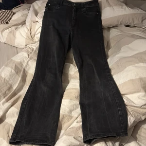 Svarta bootcut jeans med hög midja - Säljer ett par svarta bootcut jeans med hög midja i storlek M/30. Jeansen har klassisk femficksdesign och stängs med dragkedja och knapp. Perfekta för dig som gillar en lite vidare passform nertill. Dom är lite korta för mig och jag är ungefär 1,63 typ så skulle rekommendera för dom som är kortare än de. Vet inte riktigt vilket märke det är 