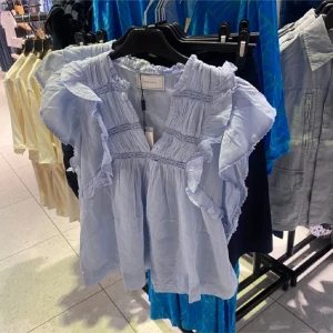 Ljusblå blus från neo noir  - Supersöt ljusblå blus från Neo noir med volangdetaljer. Blusen har v-ringning och är tillverkad i ett lätt och luftigt material, perfekt för sommaren ! 