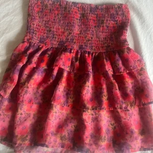 Blommig volangkjol från BikBok - Supersöt kort kjol från BikBok som är helt slutsåld i färgen rosa med blommigt mönster. Kjolen är i storlek xs men den är jätte stretchig och skulle säga att den passar xs-m i storleken. Jag bär  i vanliga fall storlek 34 i byxor och på bilden har jag vikt ner kjolen för att få den mer lågmidjat.