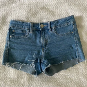 Blå jeansshorts med rå kant - Säljer ett par klassiska blå jeansshorts.  Dem är i storlek 146 men skulle säga att de passar xs. De är från Cubus oxh har ett resårband i midjan. 