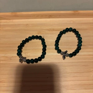 (30kr/st) Gröna armband med pärlor och bi-berlock - (30kr/st) Två elastiska armband med mörkgröna glaspärlor  och en söt liten bi-berlock i silverfärg. Perfekt accessoar för att ge din outfit en unik touch.