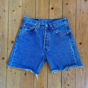 Levi's blå jeansshorts hög midja - Klassiska Levi's 501 jeansshorts i blå denim med hög midja och råa, fransiga benslut.  Perfekt vintage och snygg passform.