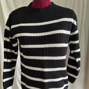 Svartvit randig stickad tröja H&M - Säljer en svart och vit randig stickad tröja från H&M. Tröjan har breda horisontella ränder, rund halsringning och är långärmad. Materialet är en mix av bomull och akryl vilket gör den både mjuk och varm. Perfekt för dig som gillar klassisk stil med en twist.