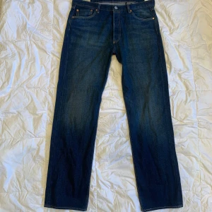 Levi's 501 Original mörkblå jeans 36/34 - Klassiska Levi's 501 jeans i mörkblå denim med raka ben och knappgylf. Snygga kontrastsömmar och femficksmodell. Perfekta för dig som gillar tidlös stil och vill ha ett par jeans som alltid funkar.