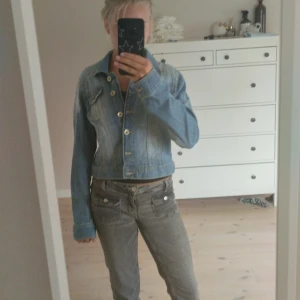 Ljusblå vintage jeansjacka - Säljer en ljusblå croppad jeansjacka från Lindex. Klassisk modell med knappar framtill, två bröstfickor med lock och långa ärmar. Jackan har en snygg tvättad denimlook och passar perfekt till jeans eller kjol. Nästan helt oanvänd💗 står inte storlek men tror att de är xs