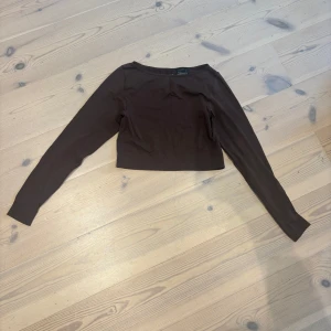 Brun croppad långärmad topp - Säljer en stilren brun croppad topp med långa ärmar. Perfekt för dig som gillar en enkel men trendig look. Toppen har en tight passform och är gjord i mjukt bomullsmaterial som känns skönt mot huden.