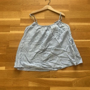 Randig blåvit linnetopp från H&M - Säljer en luftig och somrig linnetopp från H&M i storlek S. Toppen har tunna axelband och ett klassiskt blåvitt randigt mönster. Perfekt för varma dagar med sin avslappnade passform och lätta bomullsmaterial.