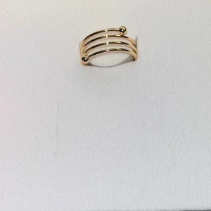 Trendig guldpläterad ring med kulor - Snygg ring i guldpläterad metall med tre parallella band och två små kulor som detalj. Den öppna designen ger en modern och cool känsla, perfekt för att lyfta din stil. Passar lika bra till statement som till lager-på-lager.