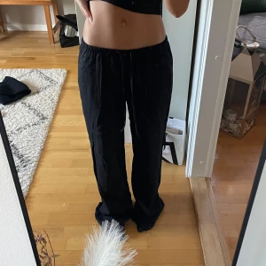 Svarta vida linnebyxor med resår - Säljer ett par svarta linnebyxor med avslappnad passform och resår i midjan. Byxorna har en loose och wide siluett, perfekta för en chill och stilren look. Materialet är lätt och svalt, vilket gör dem sköna att bära under varmare dagar. Innerbslänh: 77 midjemått:34