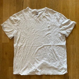 Vit v-ringad t-shirt Polo Ralph Lauren - Vit t-shirt från Polo Ralph Lauren med v-ringning och klassisk broderad logga på bröstet. Tillverkad i mjuk bomull och har en avslappnad passform. Perfekt basic-plagg för en clean och stilren look.