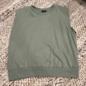 Grön ärmlös väst från Lindex - Snygg ljusgrön väst från Lindex i storlek S. Modellen är ärmlös med ribbade kanter vid halsringning och nederkant. 