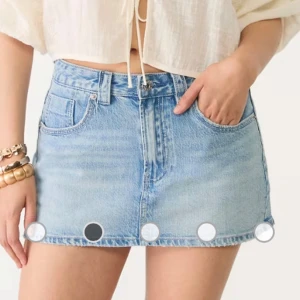 Ljusblå jeanskjol från Stradivarius - Säljer en ljusblå jeanskjol från Stradivarius med klassisk femficksdesign och rå, fransig fåll. Kjolen är kort och har bälteshällor samt dragkedja och knapp framtill. Perfekt för en chill och trendig sommarlook. Den har inbyggda shorts och jag har klippt av den där nere en bit så att den är lite kortare och har snygga slitningar
