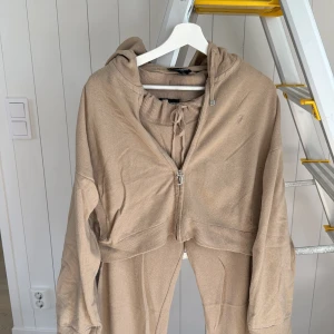 Beige mjukisset Juicy Couture L - Beiga mjukisset från Juicy Couture i storlek L. Byxorna har ribbad midja med snörning, raka ben och två bakfickor. Mjukt stickat material som känns riktigt skönt mot huden. Perfekta för chill dagar eller när du vill vara extra bekväm.