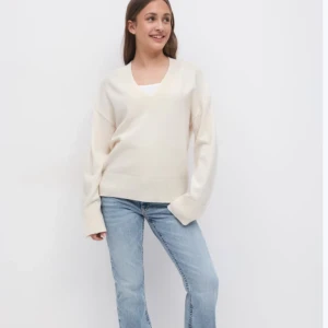 Beige stickad v-ringad tröja Gina tricot  - Supermjuk och stilren beige stickad tröja med v-ringning. Tröjan har breda ribbade muddar vid ärmslut och nederkant, vilket ger en snygg och klassisk look. Perfekt att matcha med jeans eller kjol för en chill och clean stil.