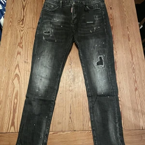 DSQUARED2 jeans - Snygga svarta jeans från DSQUARED2 med slitna detaljer och färgstänk för en cool look. De har en normal passform och är tillverkade i denim. Perfekta för dig som vill ha en edgy stil.