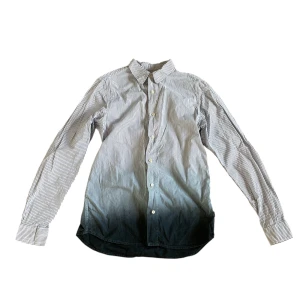 Randig skjorta från Wood Wood - Snygg randig skjorta från Wood Wood i svart och vit med en cool ombre-effekt som går från ljus till mörk. Skjortan har långa ärmar och knappar framtill. Perfekt för en stilren look.