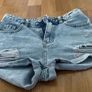 Ljusa jeansshorts med slitningar från SHEIN  - Säljer ett par ljusa jeansshorts med coola slitningar på framsidan. De har en klassisk femficksdesign och stängs med knapp och dragkedja. Perfekta för en avslappnad sommarlook! 🌞i storlek 146/10-11 år Be om mått om ni är osäkra.