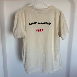 Saint Laurent T-shirt - Säljer en sällsynt vit t-shirt från Saint Laurent. T-shirten är kortärmad och gjord i mjukt bomullsmaterial. Skicket är superbra utan hål eller fläckar. Storleken är medium men passar mer mot small. Självklart är den äkta.