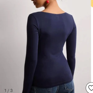 Mörkblå långärmad topp - Snygg mörkblå topp med lång ärm och en elegant fyrkantig urringning med spetsdetaljer. Perfekt för en stilren look.