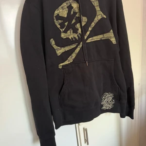  Zoo York - Säljer en svart hoodie från Zoo York med en stor dödskalle i grönt på framsidan. Hoodien har en klassisk känguruficka och justerbar dragsko i huvan. Perfekt för en cool och avslappnad stil.