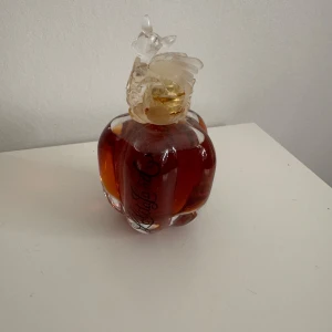 Parfymflaska med hjortmotiv - Elegant parfymflaska med en unik hjortformad kork. Flaskan har en djup bärnstensfärg och en rundad form med dekorativa detaljer. Perfekt för den som älskar unika och konstnärliga designinslag i sin parfymsamling.