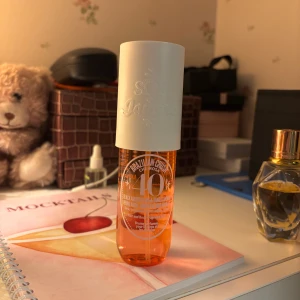 Parfymmist från Sol de Janeiro - Oanvänd. Fräsch och exotisk parfymmist från Sol de Janeiro med doft av svart bärnsten och vanilja. Flaskan är orange med en vit kork och har en praktisk sprayfunktion. Perfekt för att ge en tropisk touch till din dagliga rutin.