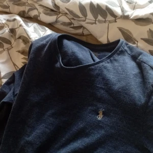 Mörkblå långärmad tröja från Polo Ralph Lauren - Säljer en stilren mörkblå långärmad tröja från Polo Ralph Lauren. Tröjan har en liten broderad logotyp på bröstet och är tillverkad i ett mjukt material. Perfekt för en avslappnad och snygg look.