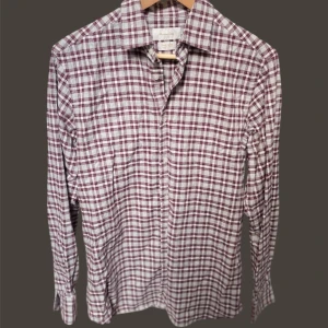 Massimo dutti skjorta  - Snygg rutig skjorta i vitt och vinrött med långa ärmar och klassisk krage. Perfekt för en stilren look. Skjortan har knappar framtill och är tillverkad i mjuk bomull.