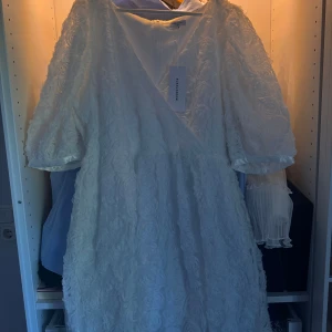 Vit klänning från Bubbleroom - Säljer en vit klänning från Bubbleroom med blommiga detaljer och omlott-design. Klänningen har trekvartsärmar, Perfekt för t.ex. studenten! Pris kan diskuteras 