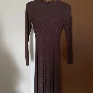 Brun glittrig långklänning - Snygg brun långklänning med glittrigt material. Aldrig använd. Passar perfekt till lite finare tillfällen. 