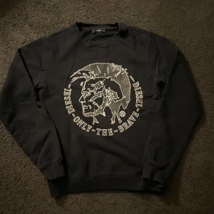 Svart sweatshirt från Diesel - Snygg svart sweatshirt från Diesel med ett stort tryck av en profil och texten 'Only The Brave' på framsidan. Tröjan har långa ärmar och en rund halsringning. Skööööön tröja