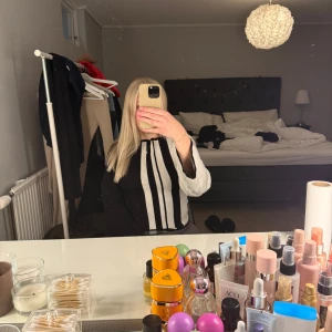 Svart och vit långärmad tröja - Säljer en stilren svart och vit tröja med långa ärmar. Tröjan har ett unikt randigt mönster framtill som ger en modern touch. Perfekt för dig som vill ha något annorlunda i garderoben!