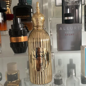 Afnan Mukhallat Abiyad Eau de Parfum - Elegant gyllene parfymflaska från afnan med en kapacitet på 100 ml. Flaskan har en lyxig design med en dekorativ topp och är tillverkad i Förenade Arabemiraten. Perfekt för den som söker en exklusiv doftupplevelse. Använt 10 sprays🤩🤩😀🤩