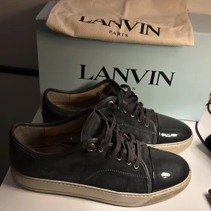 Svarta sneakers från Lanvin - Snygga svarta sneakers från Lanvin med en stilren design. Skorna har en blank tå och snörning framtill. Perfekta för en trendig look.
