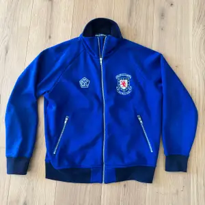 Säljer en blå tröja från Polo Sport Ralph Lauren med dragkedja och nummer 11 på ryggen. Jackan har långa ärmar och ribbade muddar. Perfekt för en sportig look!