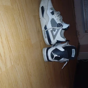 Nike Air Jordans i vit och svart - Säljer ett par klassiska Nike Air Jordans i vit och svart. Skorna har en ikonisk design med snörning och den välkända Jumpman-loggan på hälen. Perfekta för sneakerheads som vill ha en tidlös stil. De är storlek 43 dem är ej real min hund har ätit på dem men är sjukt sköna är prutbar skriv om du har några frågor eller funderingar 