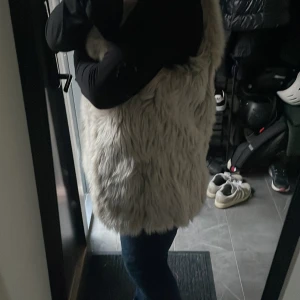 Beige pälsväst från GAP - Säljer en snygg beige pälsväst från GAP. Västen är perfekt för att hålla sig varm och stilren under kyligare dagar. Den har en mjuk och fluffig textur som ger en lyxig känsla.