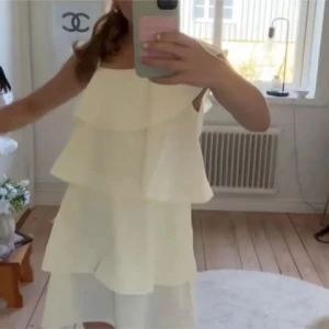 Gul volangklänning med oneshoulder - Superfin ljusgul kortklänning med flera volanger och asymmetrisk oneshoulder-design. Klänningen har smal axelrem på ena sidan och är ärmlös på andra. Perfekt för sommarens alla tillfällen och ger en fräsch och trendig look. Storlek 170