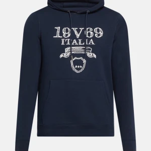 hoodie från 19V69 Italia ( Versace ) - Snygg marinblå hoodie från 19V69 Italia som är helt ny (inte tagit av lapparna än). med vit tryckt logga och emblem framtill. Tröjan har huva med snörning och en stor magficka. Tillverkad i mjuk bomullsmix, perfekt för chill dagar. Klassisk passform och långa ärmar. 