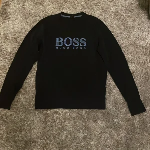 Svart BOSS sweatshirt från Hugo Boss - Navy blue sweatshirt från Hugo Boss med stort blått BOSS-tryck på bröstet. Köpt på auktoriserad butik, Hanzens, Umeå