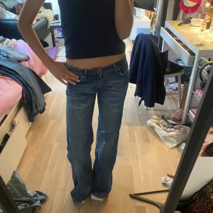 Blå bootcut jeans - Säljer ett par klassiska blå utsvängda jeans med låg midja. De har en snygg passform och är perfekta för en avslappnad stil. Jeansen har fickor både fram och bak samt en dragkedja och knapp framtill.