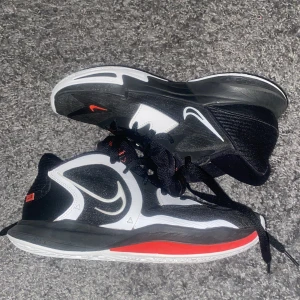 Svarta och röda Nike sneakers - Ett bra par basketskor(kyrie 5 low) i färg röd svart och vit. Använt ca 4 gånger. Normalt pris 1100kr säljs för 500kr. Riktigt bra om man kör basket. Kan också användas som idrottsskor.