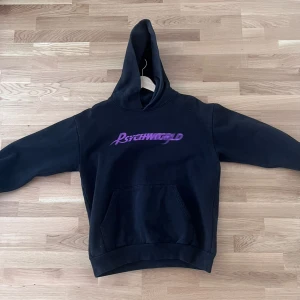 Svart Psychworld hoodie med lila tryck - Svart hoodie från Psychworld med lila logga framtill och stort grafiskt tryck på ryggen. Klassisk känguruficka och huva. Perfekt för dig som gillar streetwear och vill sticka ut med coola detaljer. Pris går självklart att diskuteras storlek L