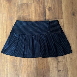 Svart flared mini kjol - Snygg svart flared mini kjol som jag har köpt från Mings london. Jag säljer den eftersom den är lite för stor för mig. Midjemåttet tvärs över är 41 cm och den är 35 cm lång. Kjolen knäpps med en liten dragkedja. 