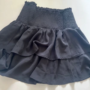 Svart volangkjol med smock - Supersöt Kort volangkjol, ny utan prislapp. Skriv om ni undrar något💕