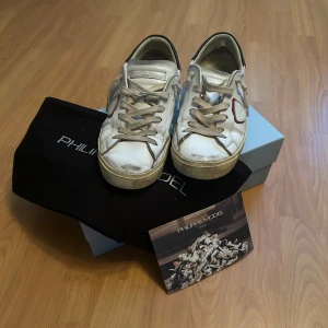 Vita Philippe Model sneakers med röd detalj - Tja säljer dessa Philip models till ett riktigt bra pris skicket på dom är riktigt bra och pris kan diskutera nypris på dessa är runt 3 tusen hör av er om ni är intresserade box och dustbag följer inte mef