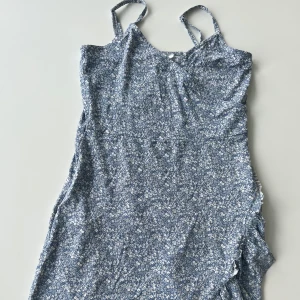 Ljusblå klänning från Gina Tricot - Supersöt ljusblå klänning med vita småblommor från Gina Tricot. Den har smala axelband och en lätt figurnära passform. Perfekt för varma dagar och ger en fräsch sommarkänsla. Tunt och mjukt material. Storlek 158/164 men passar även XXS/XS.