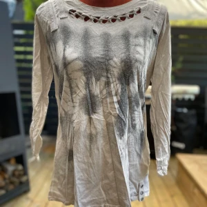 Ljusgrå långärmad topp med snörning BSR 40 - Långärmad tröja med dekorativa detaljer fram och bak. Tröjan har blomstertryck med utskurna partier och en speciell färgning. Längd: 69 cm ﻿Bystvidd: 49 cm 100% bomull  Inga bilder när den sitter på mig! Katter finns i hemmet!